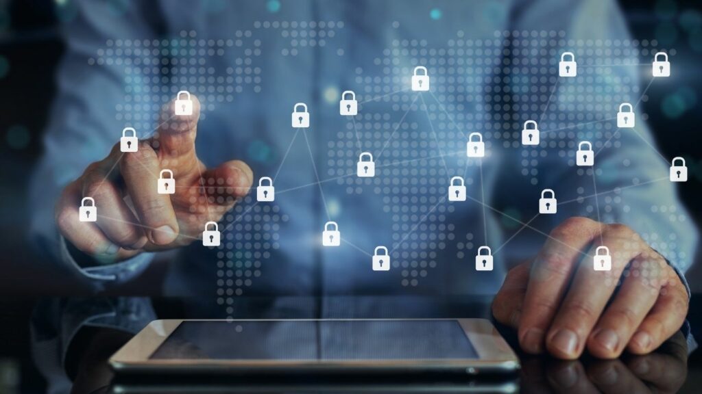 Profissional tocando tela digital com ícones de cadeados conectados, simbolizando a proteção de dados e sistemas na era da hiperconectividade e a importância da cibersegurança corporativa.